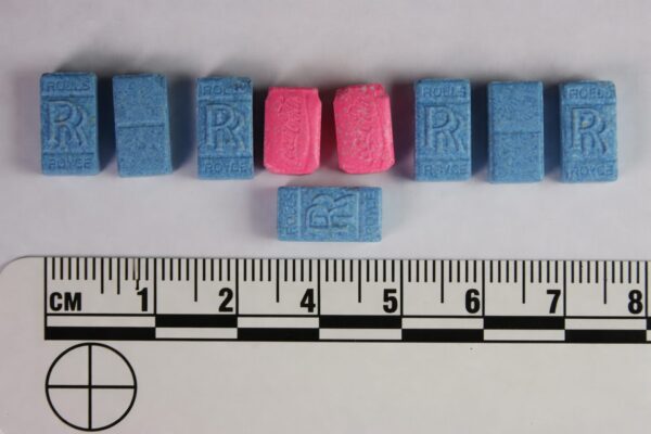 Blue and pink Rolls Royce ecstasy pills arranged with ruler scale showing size and shape of MDMA tablets